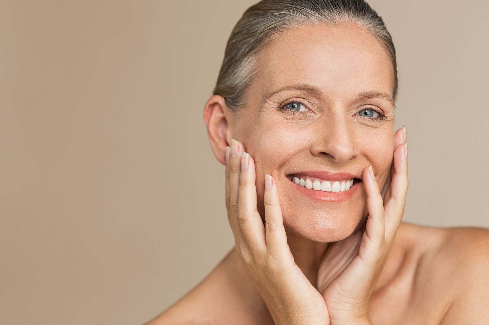 Beauty portrait of mature woman smiling with hand on face. Closeup face of happy senior woman feeling fresh after anti-aging treatment. Smiling beauty looking at camera with perfect skin.