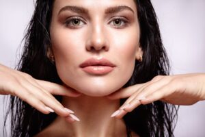 Portrait of a young brunette woman with shining wet make-up and shiny moist long hair hairdo